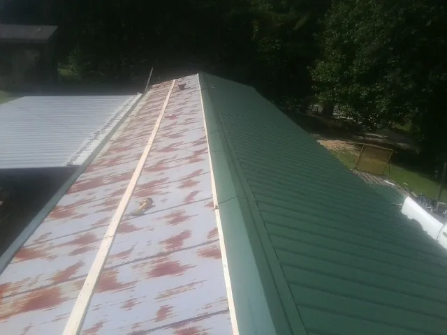 Old rusted panels beside newly installed green metal roofing — Wind Damage Roof Repair by Roofing Brothers in Bridgeport