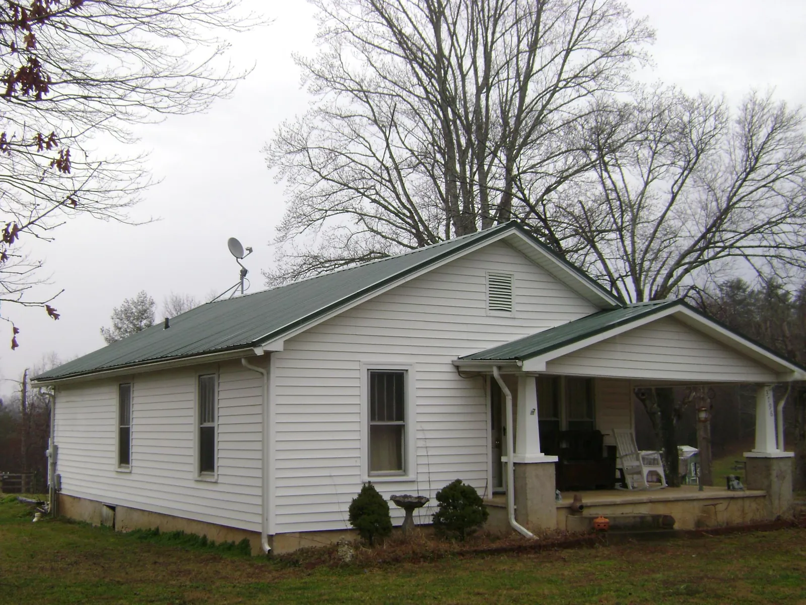 Green metal roof on a white bungalow with a side porch in Bridgeport