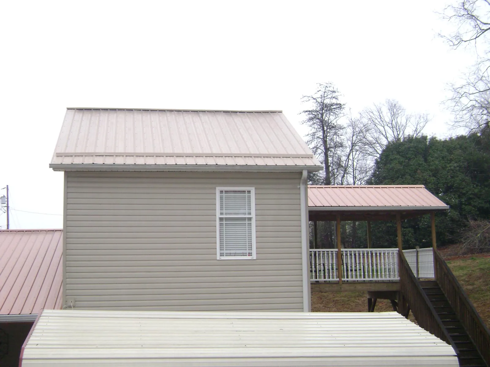 Tan metal roofs on a two story addition and attached porch, from a Roof Replacement job in Bridgeport